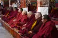 Mönche in roten Gewändern sitzen in Reihen und meditieren oder nehmen an einer Zeremonie teil.