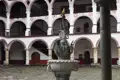 Brunnen im Innenhof eines Klosters mit umliegenden Arkaden und Balkonen.