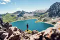 Wanderer mit Blick auf einen türkisblauen Bergsee in den Alpen.