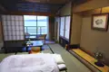 Innenansicht eines traditionellen japanischen Hotelzimmers mit Meerblick durch die Balkontür. Tatami-Matten, niedriger Tisch und traditionelle Schiebetüren sind sichtbar.