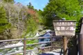 Ryuzu-Wasserfälle im Nikko-Nationalpark mit einem Schild, das den Namen des Wasserfalls und des Parks angibt.