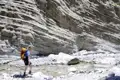 Wanderer durchquert einen Flussbett in einer felsigen Schlucht.
