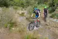 Zwei Mountainbiker durchqueren einen Bach während ihrer Tour.