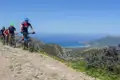 Drei Mountainbiker genießen die Aussicht während einer Fahrt entlang der Küste.