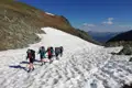 Wanderer überqueren ein Schneefeld in den Bergen.
