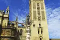 Die Giralda, der Glockenturm der Kathedrale von Sevilla, ragt vor einem blauen Himmel empor.