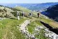Wanderer auf einem Bergweg mit Blick auf eine Burgruine und die Landschaft.