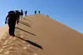 Wandergruppe besteigt eine Sanddüne.