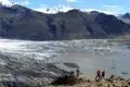 Touristen beobachten einen Gletscher und einen Gletschersee.