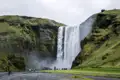 Der imposante Skógafoss Wasserfall in Island mit Besuchern im Vordergrund.