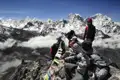 Wandergruppe auf einem Berggipfel mit Blick auf die schneebedeckten Himalaya-Gipfel.