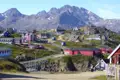 Farbenfrohe Häuser in einer grönländischen Siedlung, umgeben von einer bergigen Landschaft.