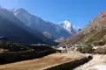 Bergdorf im Himalaya mit schneebedeckten Gipfeln im Hintergrund.