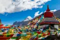 Gebetsfahnen flattern im Wind vor einer Stupa mit dem Berg Kailash im Hintergrund.