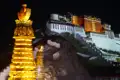 Der Potala-Palast, ein historisches Wahrzeichen Tibets, wird bei Nacht beleuchtet. Im Vordergrund befinden sich beleuchtete Stupas.