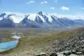 Panoramablick auf schneebedeckte Berge, Seen und ein Geröllfeld, typisch für die Landschaft der Region.