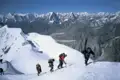 Bergsteiger mit Ausrüstung beim Aufstieg eines verschneiten Gipfels im Himalaya.