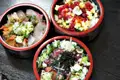 Drei Schalen mit verschiedenen Fischgerichten, darunter roher Fisch, möglicherweise Thunfisch oder ein ähnlicher Fisch, sowie ein Gericht mit Reis und verschiedenen Toppings.