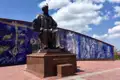Statue von Mirzo Ulugbek mit einem blauen Mosaik im Hintergrund.