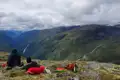 Wanderer machen eine Pause und bewundern die Aussicht auf das Tal, einen Wasserfall und die umliegenden Berge.
