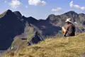 Wanderer pausiert auf einem Berggipfel und betrachtet die Berglandschaft.