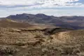 Ausblick auf eine trockene, bergige Landschaft mit spärlicher Vegetation und tiefen Schluchten.