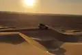Geländewagen auf einer Düne im Sonnenuntergang.