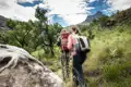 Zwei Wanderer auf einem Bergpfad. Im Hintergrund ist ein Berg zu sehen.