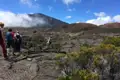 Wandergruppe auf einem Lavafeld, Vulkanlandschaft im Hintergrund.