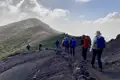 Wandergruppe auf einem Vulkanpfad, umgeben von vulkanischem Gestein und spärlicher Vegetation.