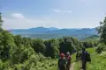 Wandergruppe auf einem Bergpfad mit Blick auf eine weite Berglandschaft.