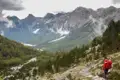Wanderer auf einem Bergpfad mit Blick auf ein Tal und die umliegenden Berge.