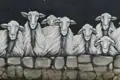 Wandmalerei mit mehreren Schafen hinter einer Steinmauer.