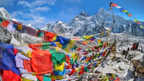 Gebetsfahnen wehen im Wind vor der Kulisse des schneebedeckten Mount Everest.