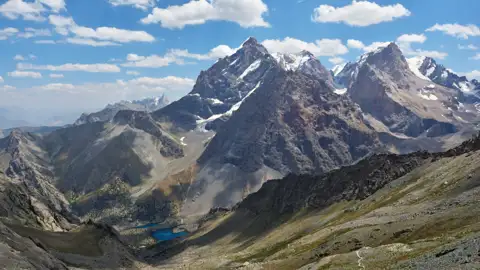 Schneebedeckte Berggipfel und ein Tal im Vordergrund.