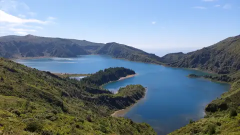 Der Kratersee, umgeben von üppiger Vegetation und vulkanischen Hügeln.