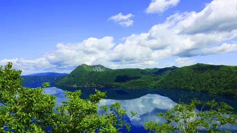 Panoramablick auf einen ruhigen See und grüne Hügel.