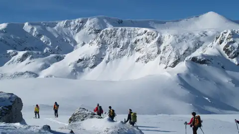 Skitourengeher durchqueren eine verschneite Berglandschaft.