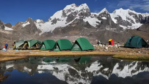 Basislager in den Bergen mit Zelten und einem kleinen See.