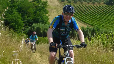 Mountainbiker auf einem Weg inmitten von Weinbergen.