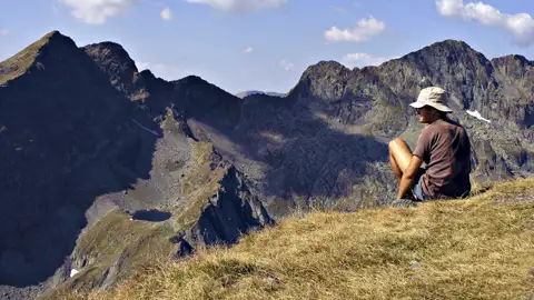 Wanderer pausiert auf einem Berggipfel und betrachtet die Berglandschaft.