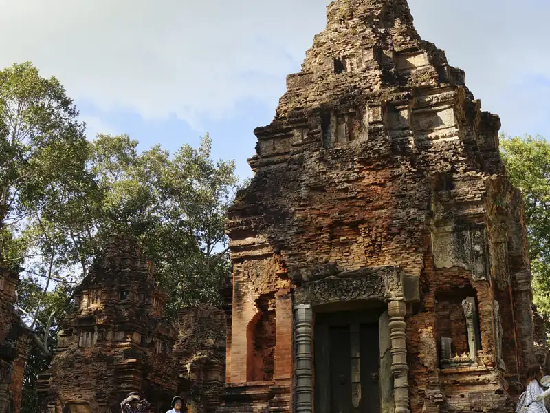Kambodscha Radreise. Verwitterte Steinruine eines antiken Tempels mit detaillierten Schnitzereien am Eingang.