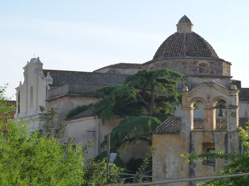 Alte Kirche mit Kuppel und Glockenturm, umgeben von Grün.