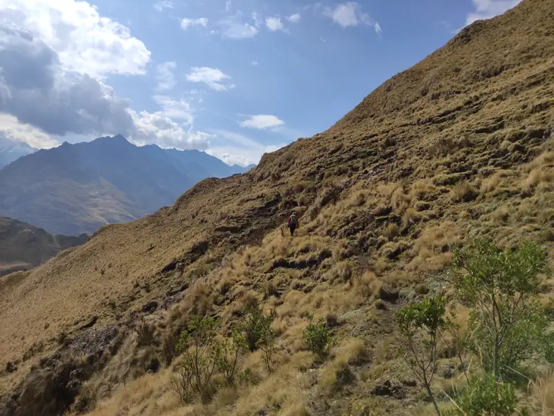 Wanderer auf einem grasbewachsenen Berghang mit Blick auf die Berge.