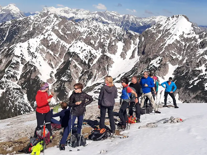 Wandergruppe pausiert im Schnee mit Blick auf die Berglandschaft.
