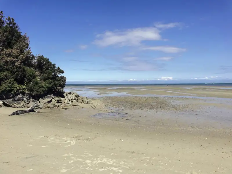 Strand bei Ebbe mit Felsen und Blick auf das Meer.