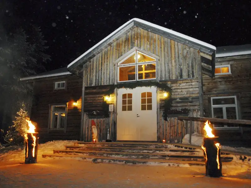 Holzhaus mit Fackeln im Schnee