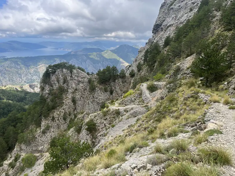 Schmaler Bergpfad mit Blick auf eine Bucht im Hintergrund.