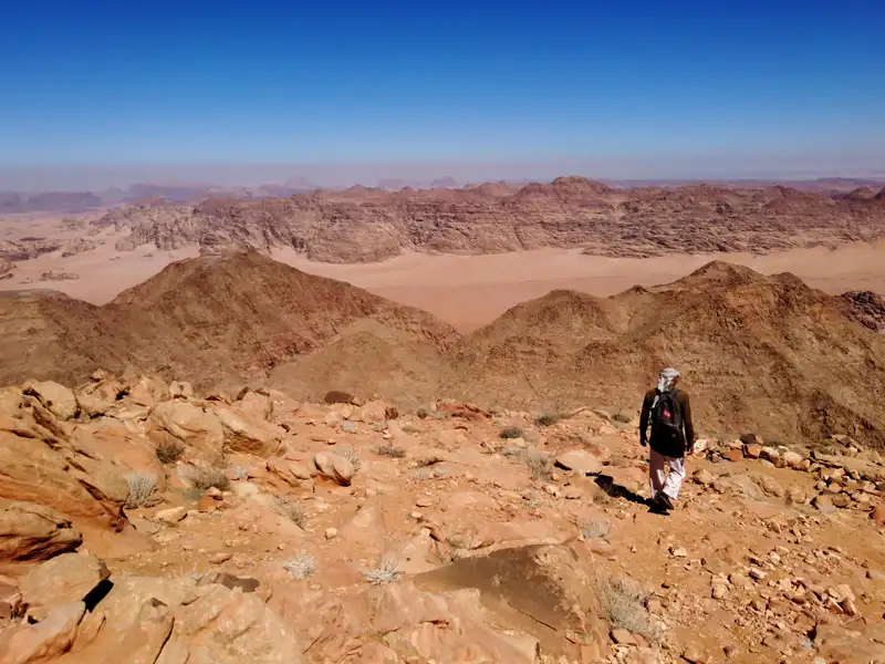 Ein Wanderer mit Rucksack wandert durch die felsige Wüstenlandschaft.