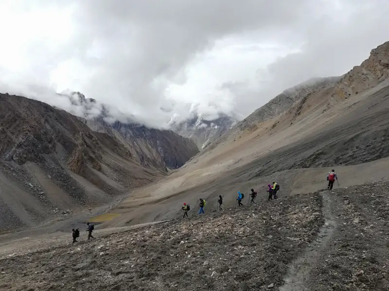 Wandergruppe auf einem Bergpfad in einer kargen, felsigen Landschaft.
